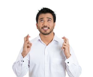 Closeup portrait of a young handsome man crossing fingers wishing and praying for miracle, hoping for the best, isolated on white background. Positive human emotion facial expression feelings attitude