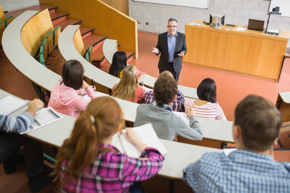 Elegant teacher with students sitting at the college lecture hall