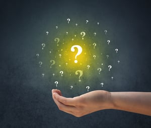 Yellow question marks hovering over young hand