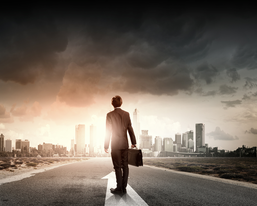 Rear view of businessman with suitcase standing on road Rear view of businessman with suitcase standing on road
